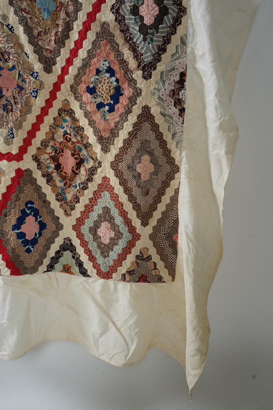 An ornate 19th century Log Cabin patchwork, made mostly from printed dress cottons from 1850-1900. 195cm long x 157cm wide., Condition - The colours are still bright and cotton strong. The patchwork backing and the cream